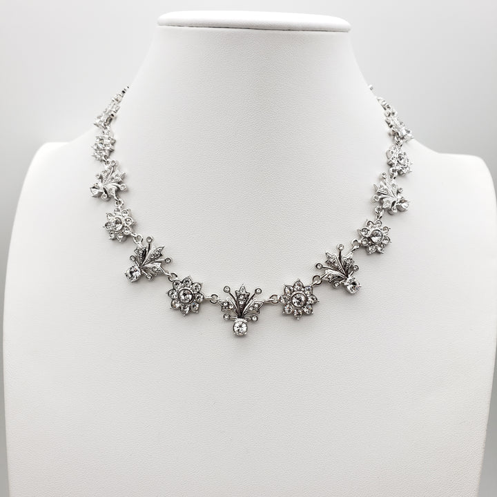 Silver floral necklace on a mannequin bust against a white background
