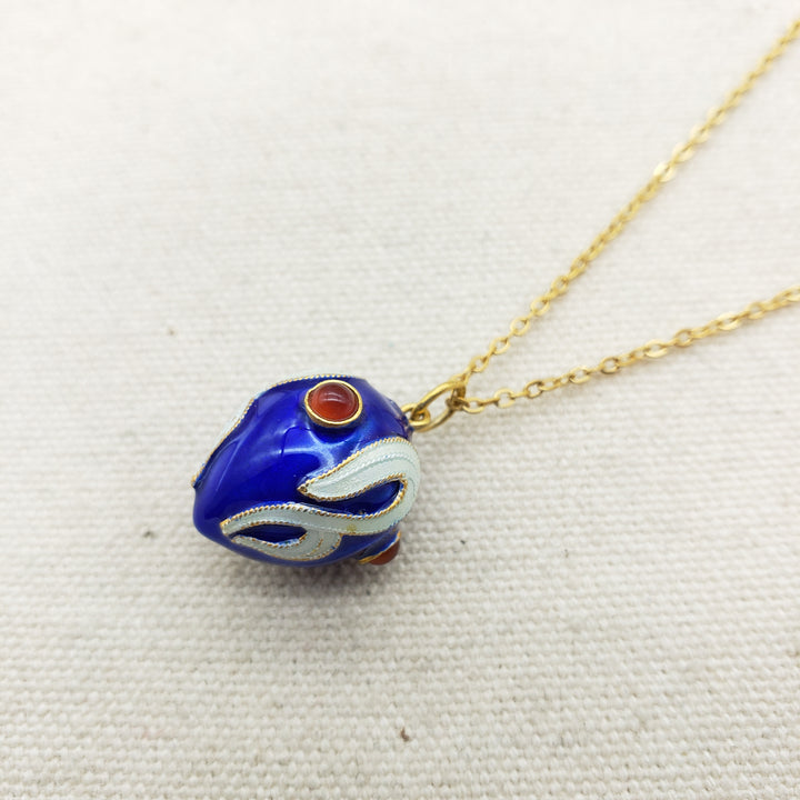 Blue fish-shaped pendant on a gold chain against a white background