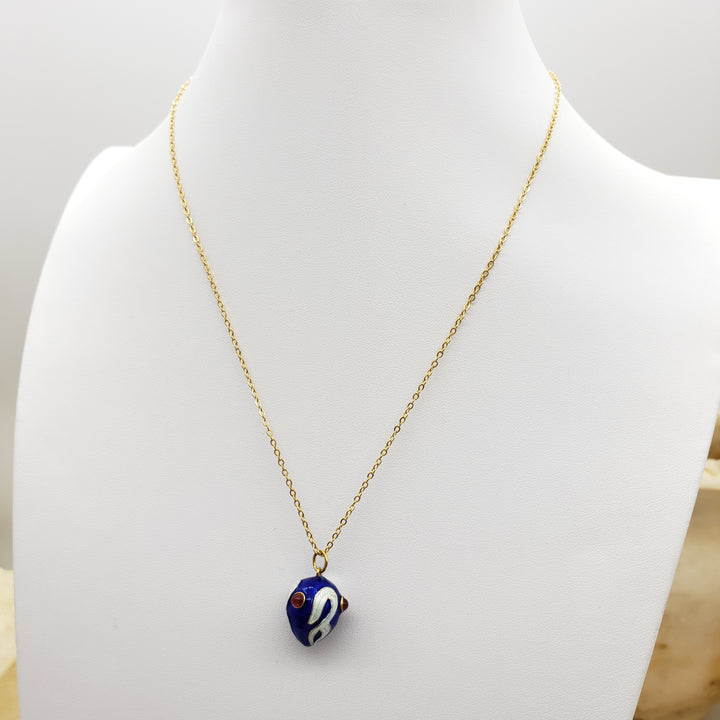 Gold necklace with a blue pendant on a mannequin bust.