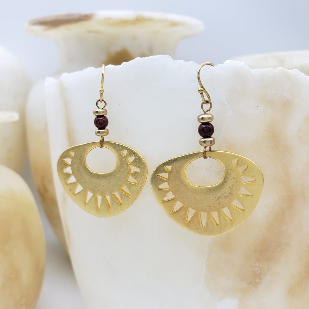Gold earrings with a central bead on a shell background