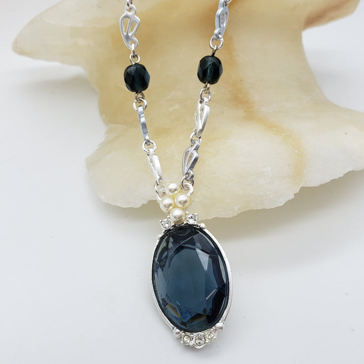 Necklace with dark blue pendant and black beads on a white background