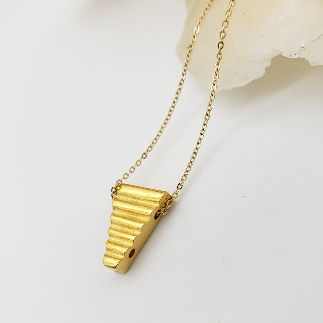 Gold triangle pendant on a chain against a light background