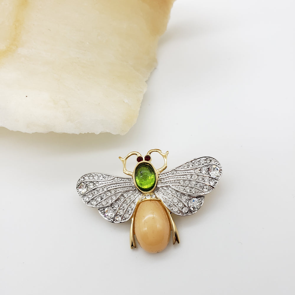 Jewelry item resembling a bee with gemstones on a white background
