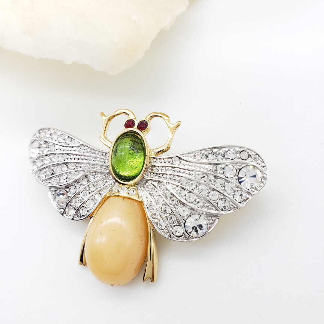 Insect-shaped brooch with gemstones on a white background