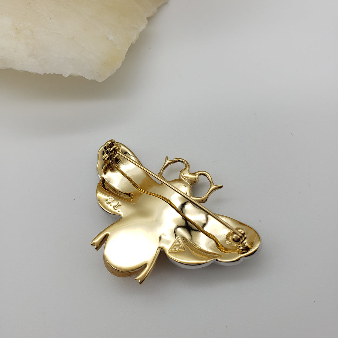 Gold brooch with intricate design on a light gray background