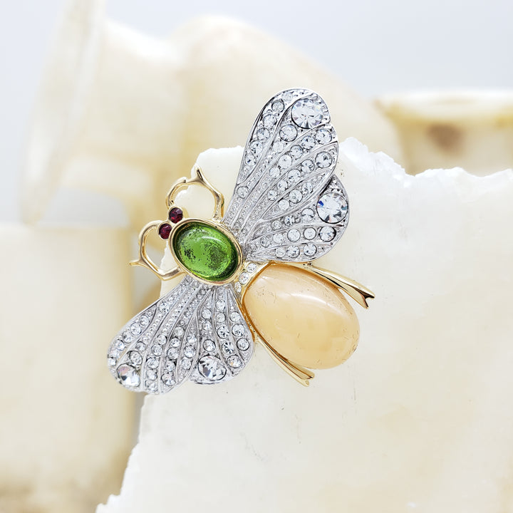 Butterfly-shaped brooch with gemstones on a shell background