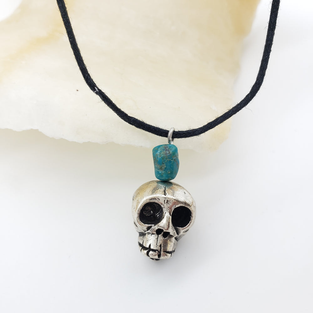 Necklace with skull pendant and blue bead on a white background