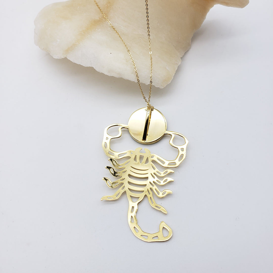Gold scorpion pendant necklace on a white background