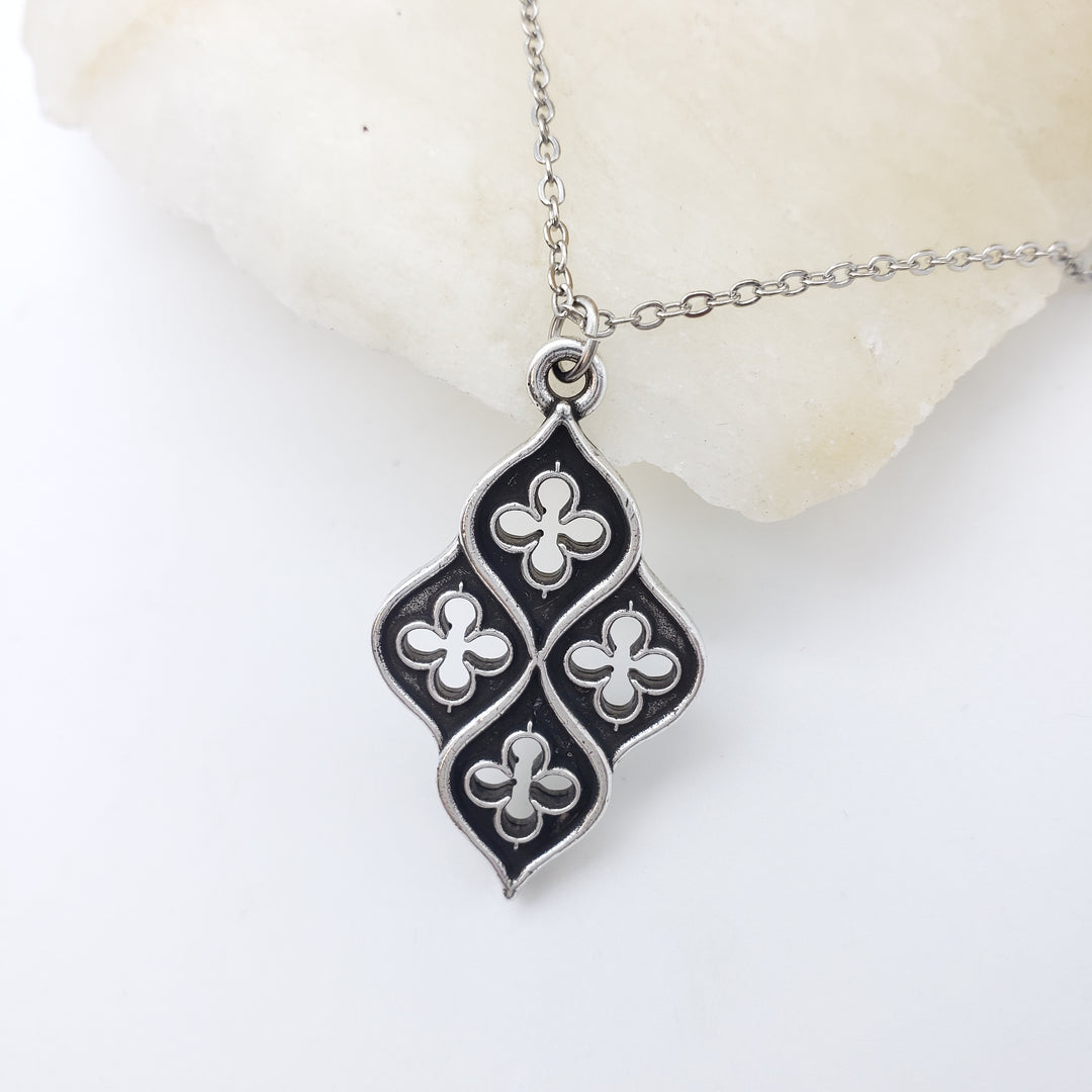 Silver necklace with a black and white clover pendant on a white background