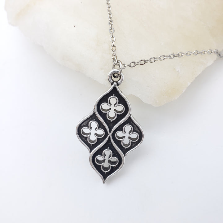 Silver necklace with a black and white clover pendant on a white background