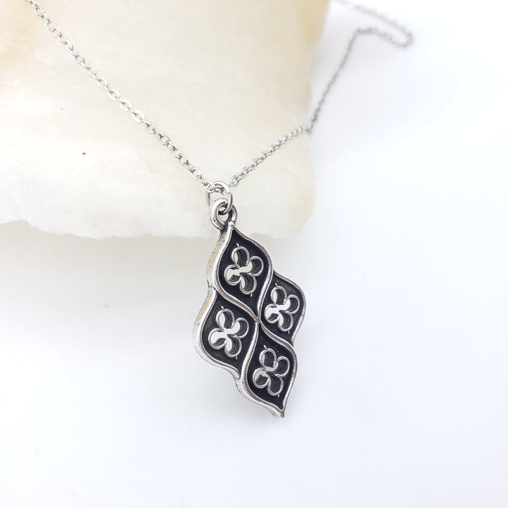 Silver necklace with a black and white pendant on a white background