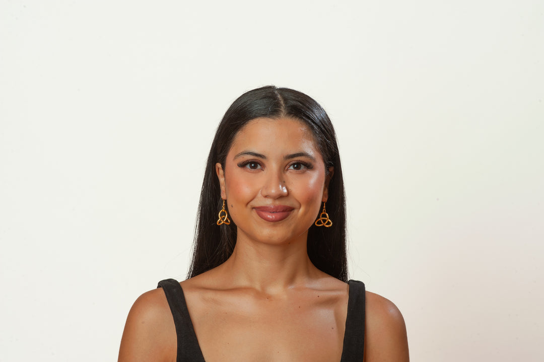 Woman wearing gold earrings against a plain background