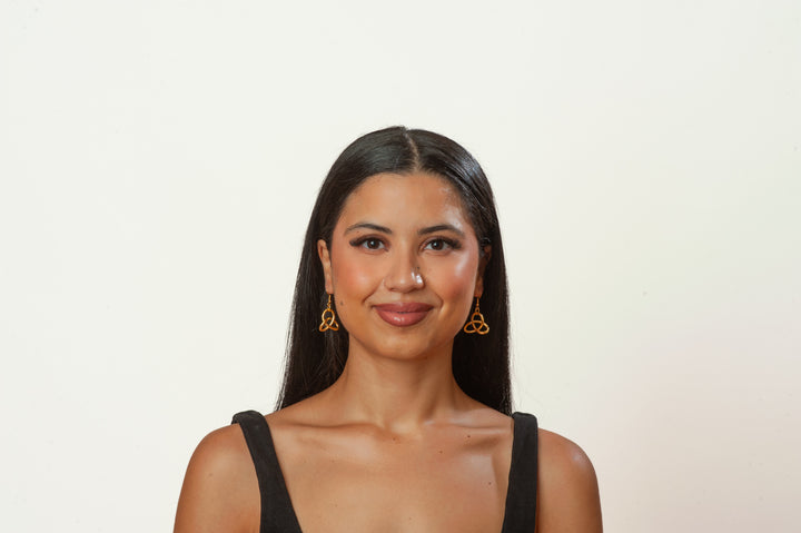Woman wearing gold earrings against a plain background