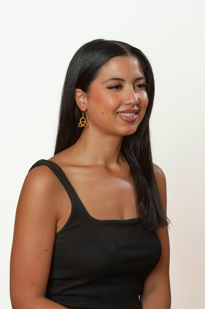 Woman wearing a black tank top against a plain background