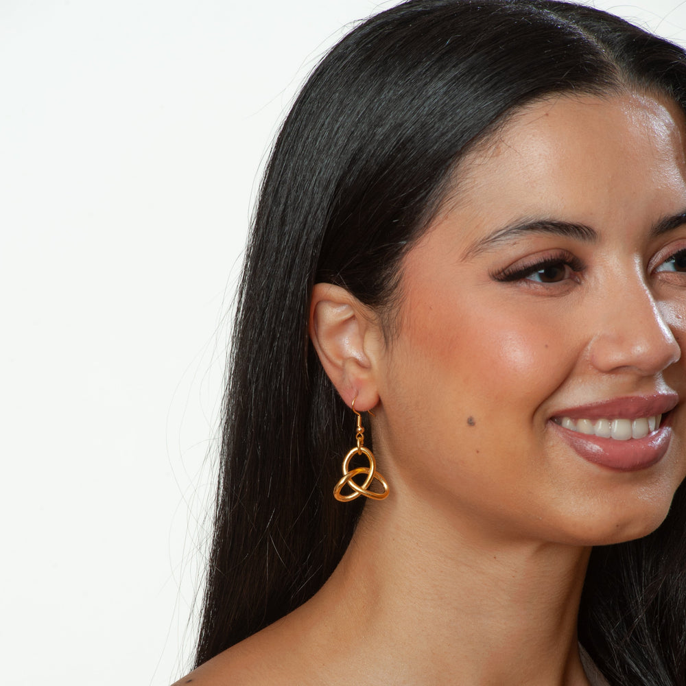 Woman wearing gold earrings with a plain background