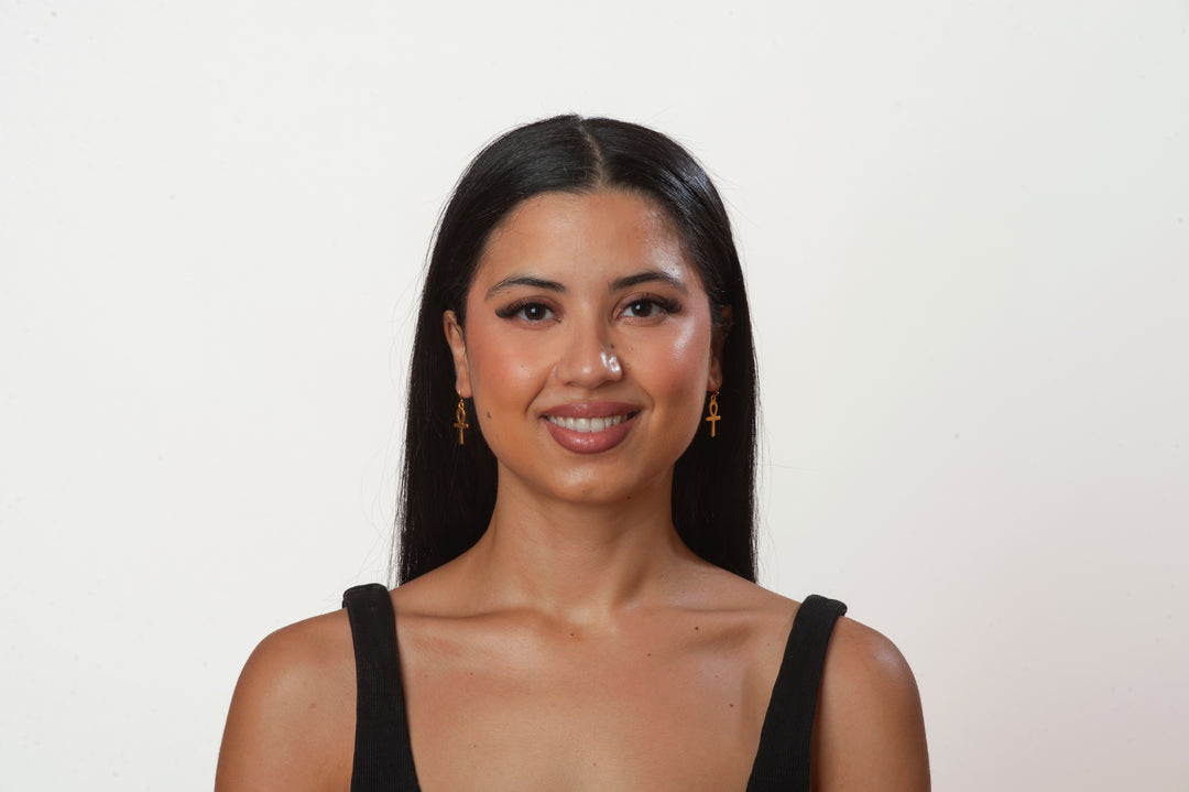 Woman with long dark hair wearing a black top against a plain background