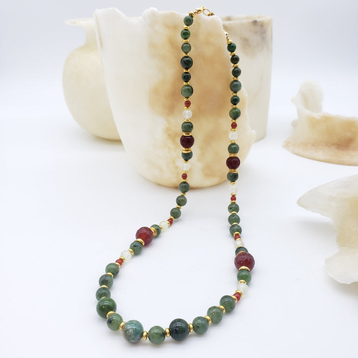 Necklace with green and red beads on a shell and white background
