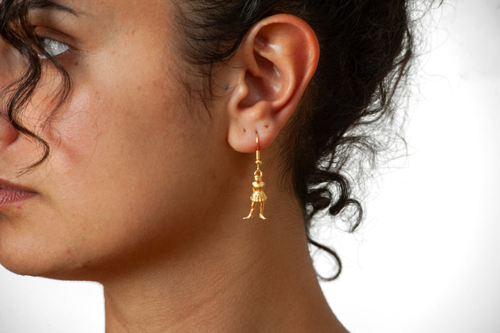 Close-up of a woman wearing gold earrings with a neutral background