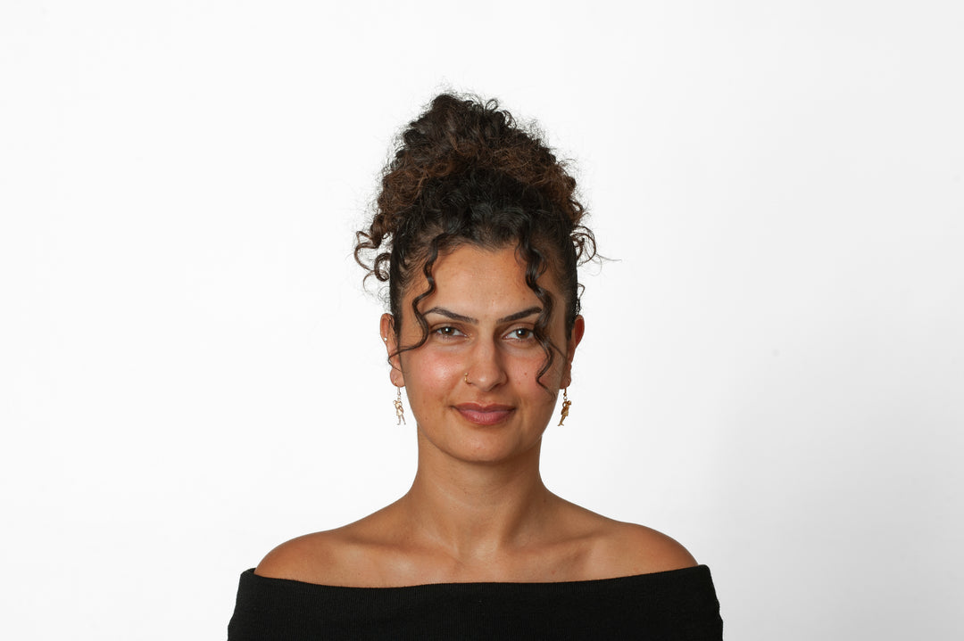 Woman with styled hair wearing earrings against a white background