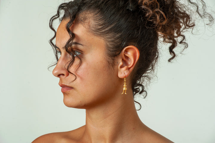 Woman wearing gold earrings against a plain background
