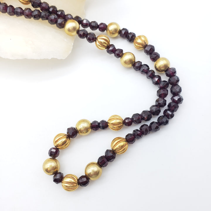 Necklace with gold and dark red beads on a white background