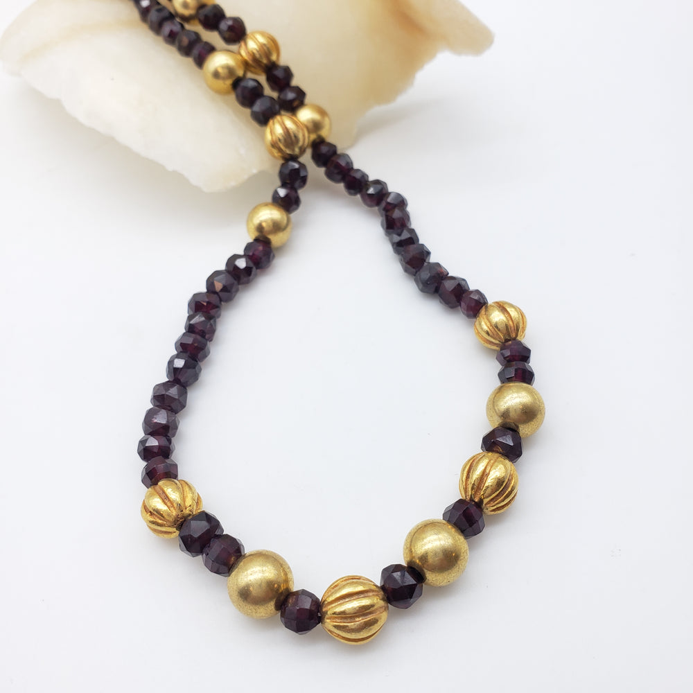 Necklace with gold and dark red beads on a white background
