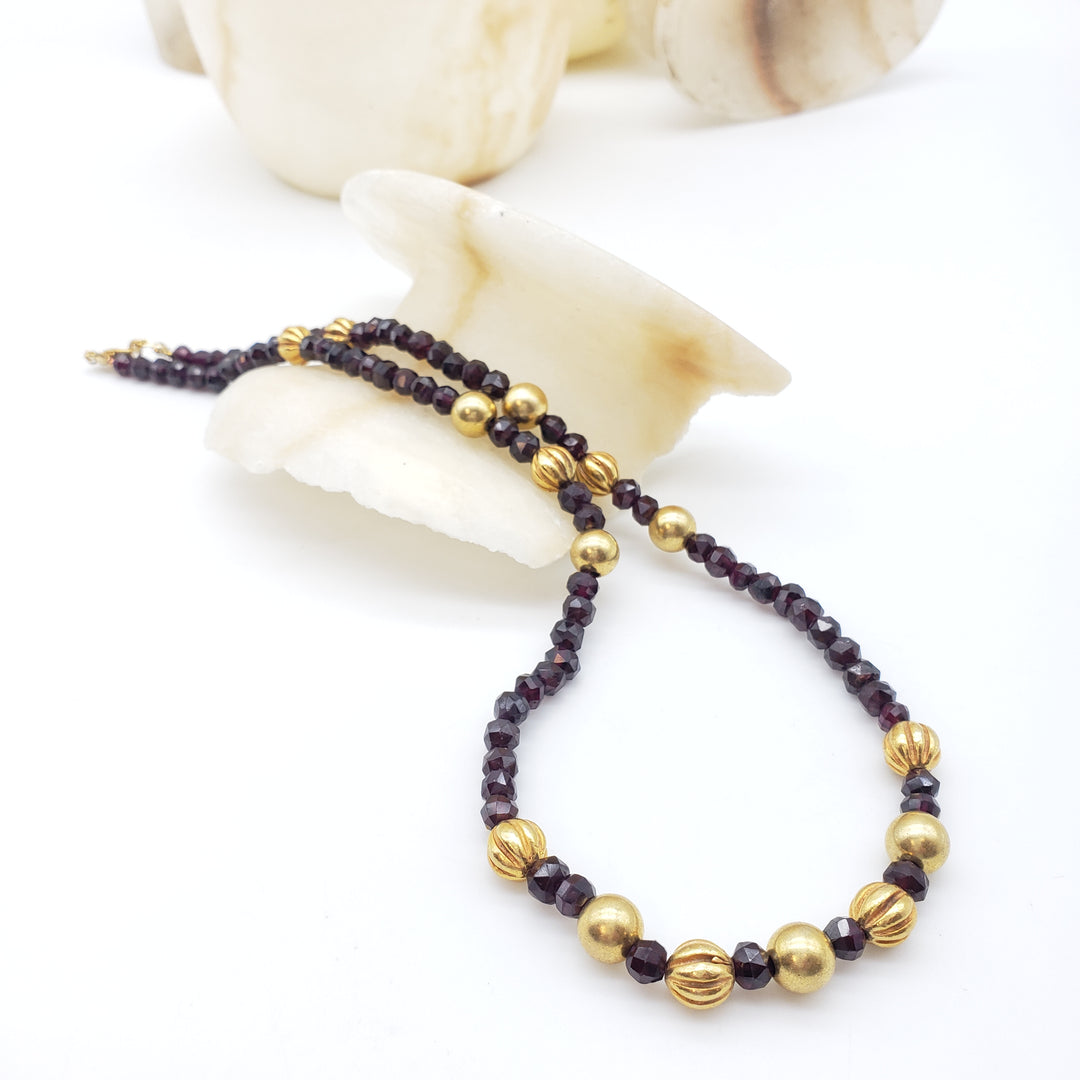 Necklace with gold and dark red beads on a white background