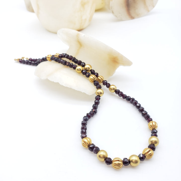 Necklace with gold and dark red beads on a white background