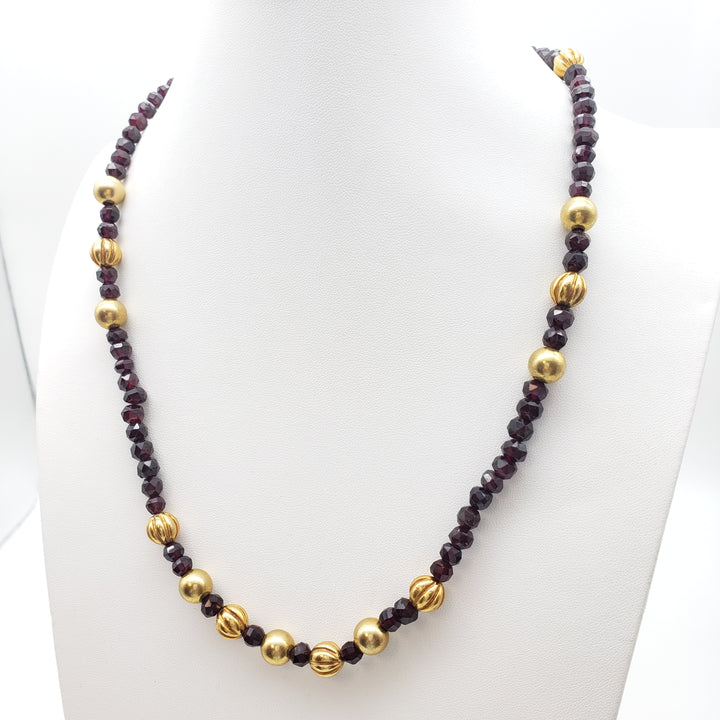 Necklace with gold and dark red beads on a white surface