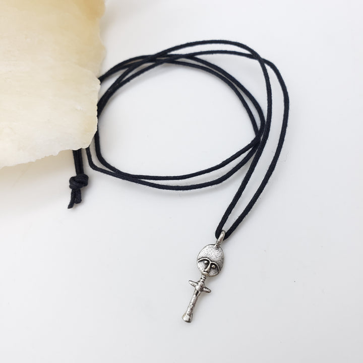 Black cord necklace with a silver akuaba doll on a white background