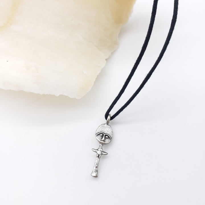Black cord necklace with a silver akuaba doll on a white background