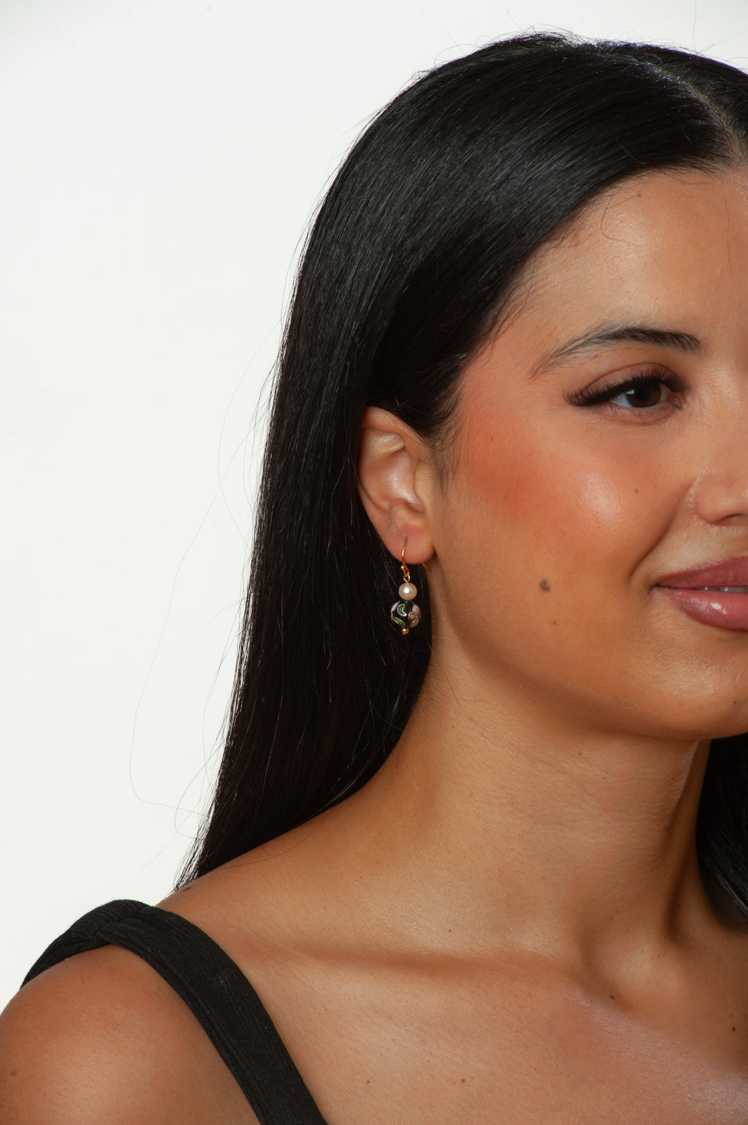 Close-up of a woman with long dark hair and earrings against a white background