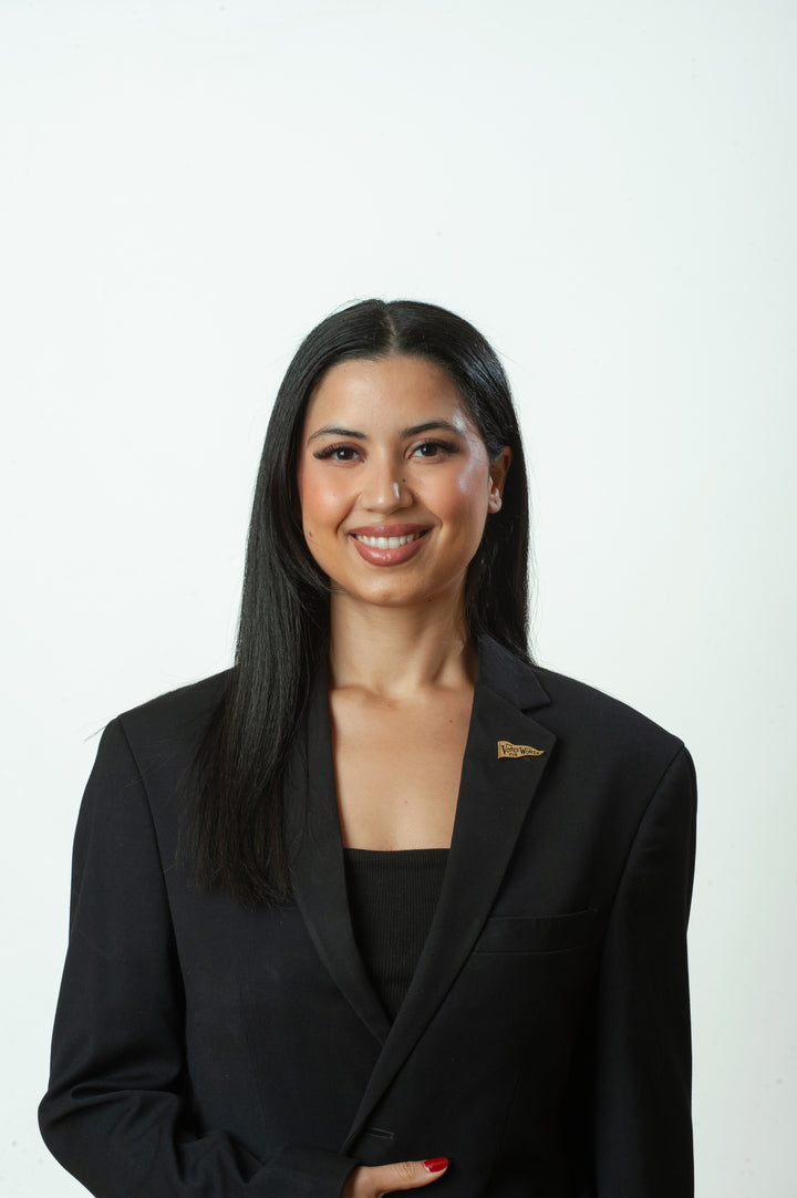 Woman wearing a black blazer with a visible logo on a white background