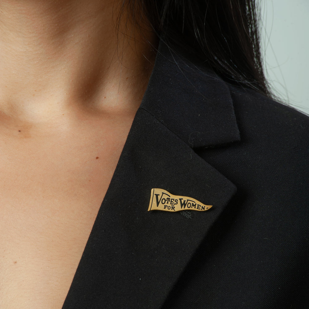 Black blazer with a 'Votes for Women' pin on a blurred background