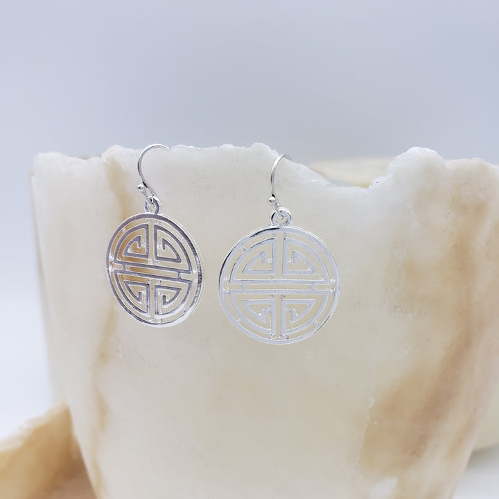 Silver earrings with intricate design on a white surface