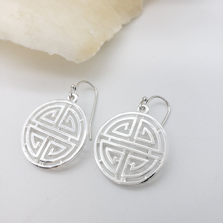 Silver earrings with intricate design on a light gray background