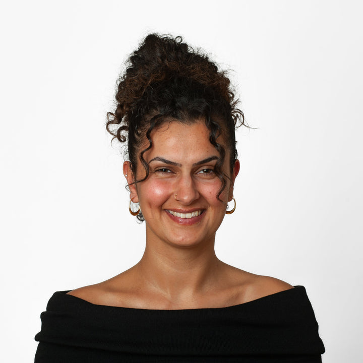 Woman with styled hair wearing a black off-shoulder top against a white background