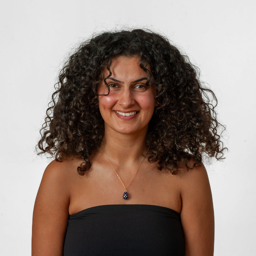 Woman with curly hair wearing a black strapless top against a white background