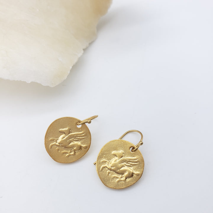 Gold Pegasus earrings on a white background