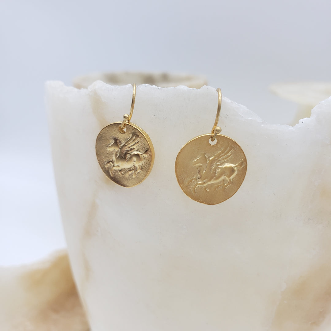 Gold circular earrings on a white surface
