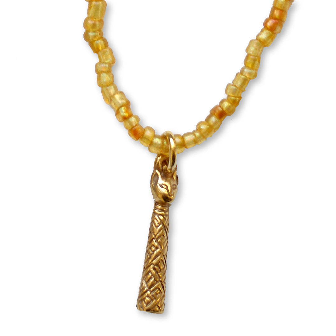 A gold-toned beaded necklace featuring a stylized cat head pendant and a textured cylindrical charm, displayed on a clean white background.