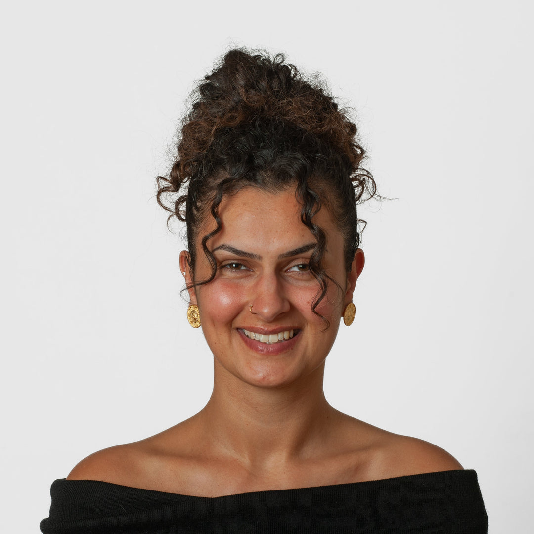Woman with styled hair wearing a black off-shoulder top against a plain background