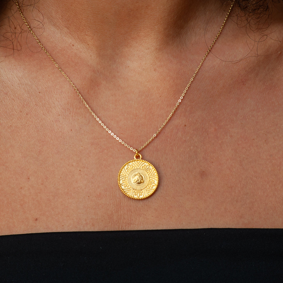 Gold necklace with a round pendant on a person's neck