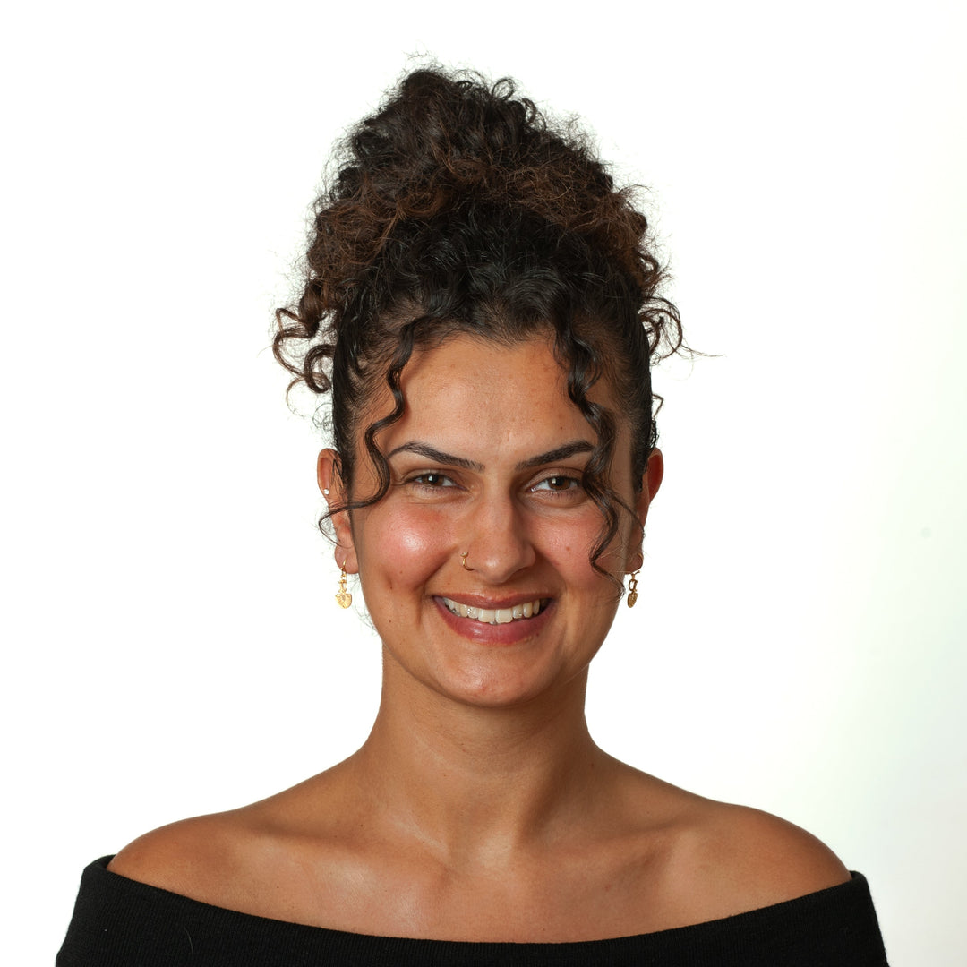 Woman with styled hair and a black off-shoulder top against a white background