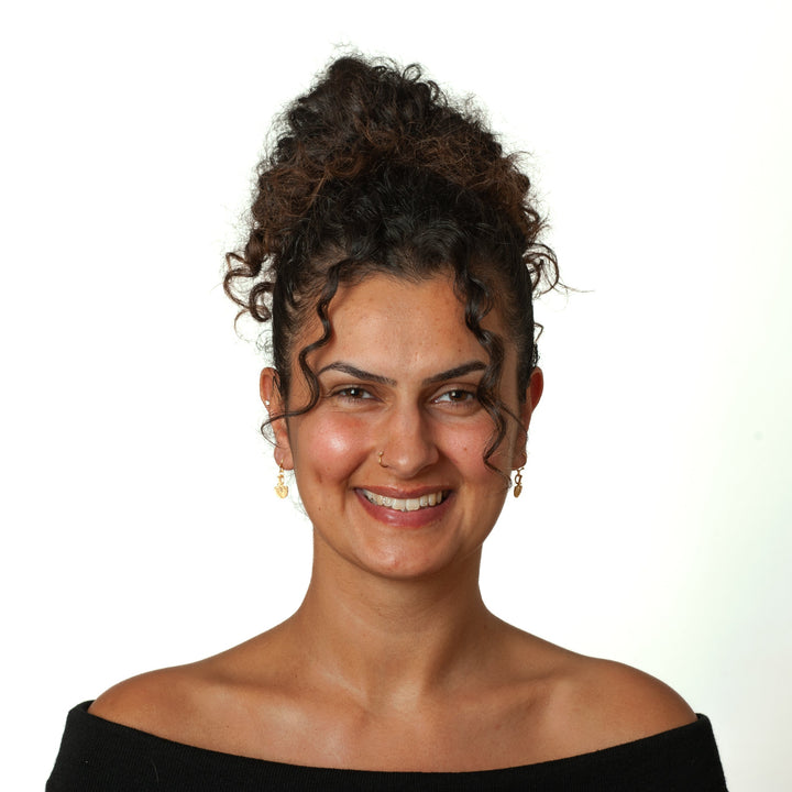Woman with styled hair and a black off-shoulder top against a white background