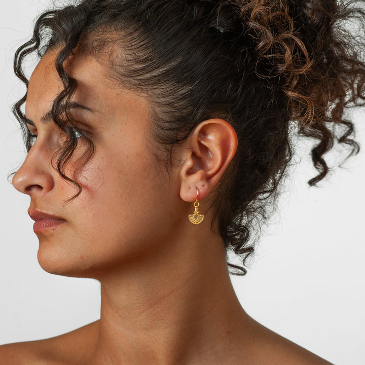 Close-up of a woman's profile with an earring on a plain background