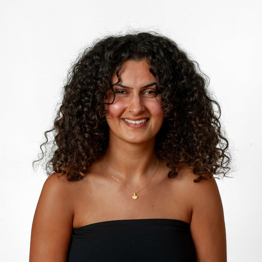 Woman with curly hair wearing a black strapless top against a white background