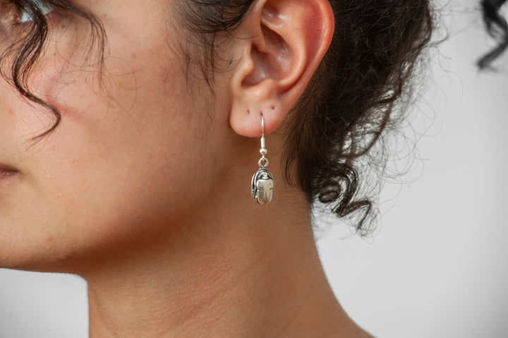 Close-up of a person wearing a silver earring with a small round pendant.