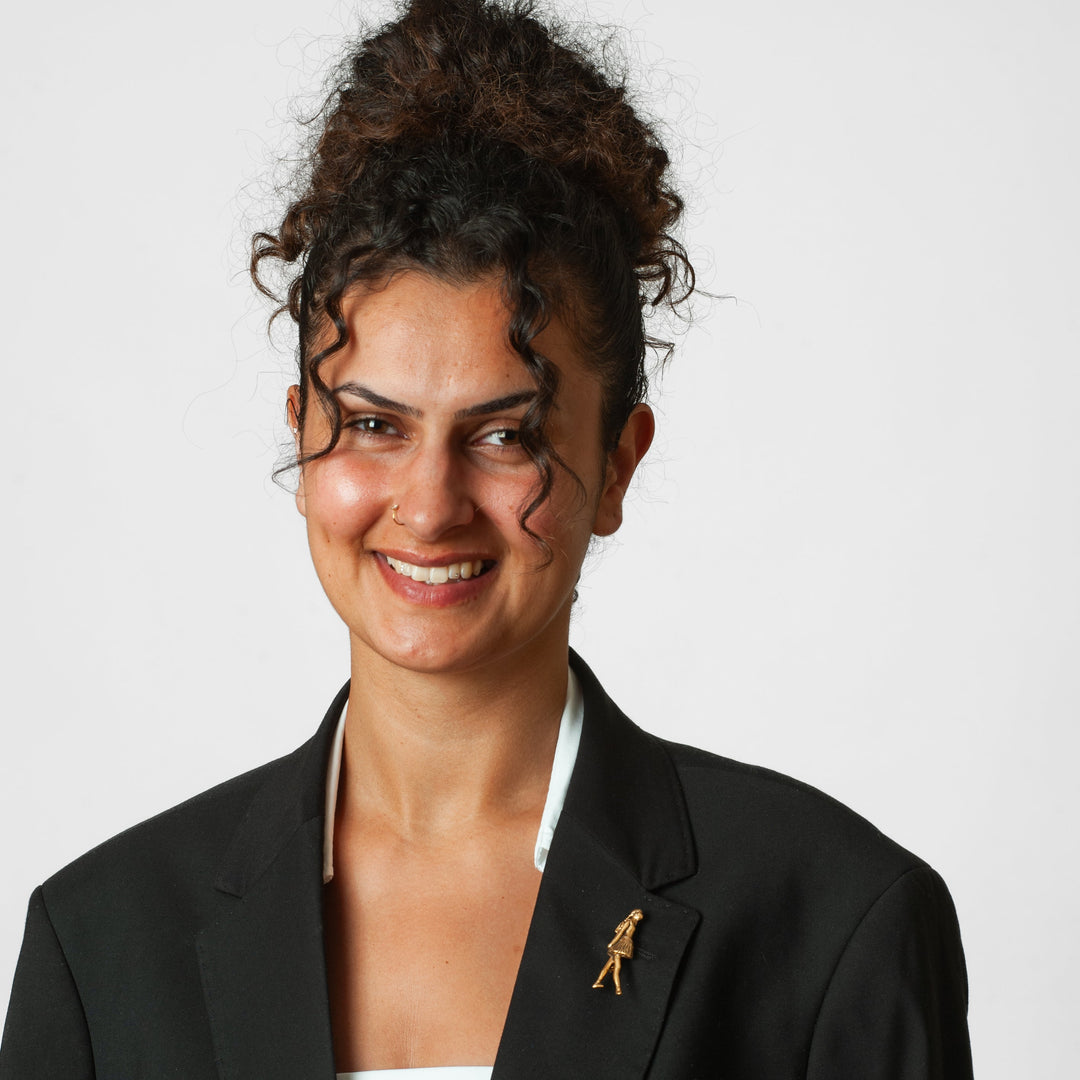 Woman wearing a black blazer with a brooch on a white background