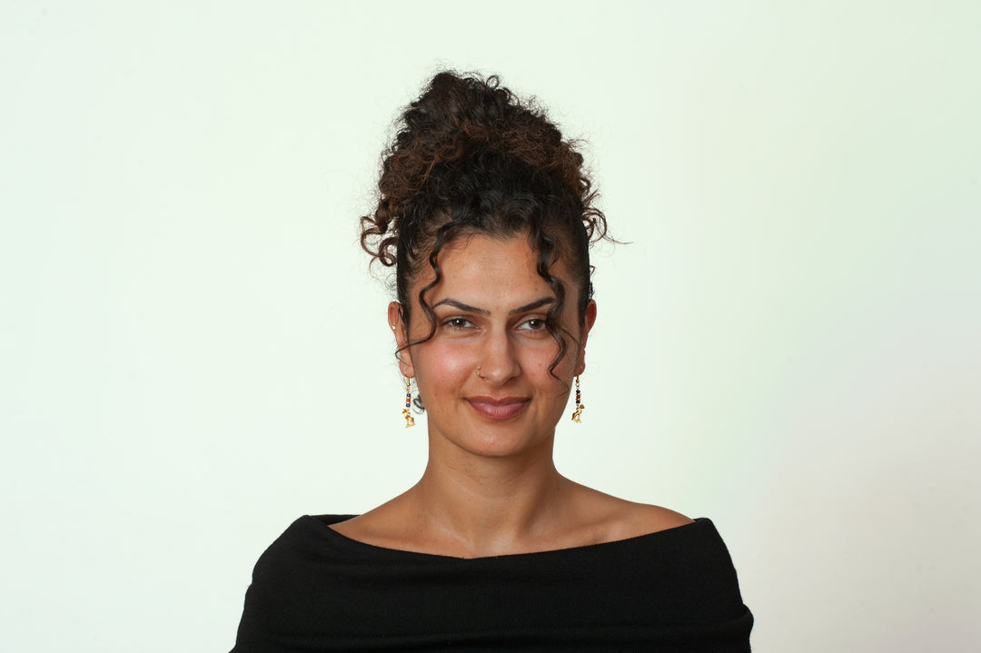 Woman with styled hair wearing a black off-shoulder top against a light background
